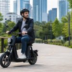 Helmeted adult riding a seated electric scooter on a protected city path