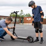 Adult checking an electric scooter before a helmeted 12-year-old rider uses it